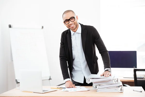 Young handsome businessman standing at the desk in the office — Stock Photo, Image