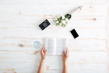 Ahşap masada kitap tutan kadın elleri