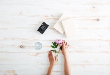 Women hands with peony flower on the wooden desk