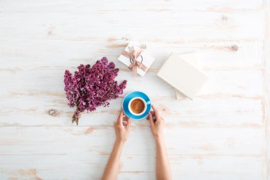 Ahşap masada kahve içen genç kadının elleri