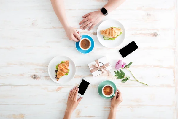Руки мужчины и женщины завтракают на деревянном столе — стоковое фото