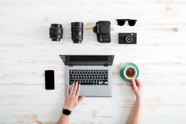 Hands of man using laptop and drinking coffee on table — Stock Photo, Image