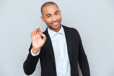 Genç adam Tamam işareti gri arka plan üzerinde gösterilen