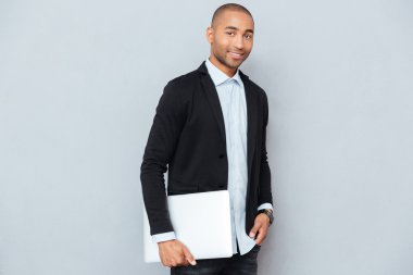 Ayakta ve tutan laptop yakışıklı Afrikalı-Amerikalı genç adam