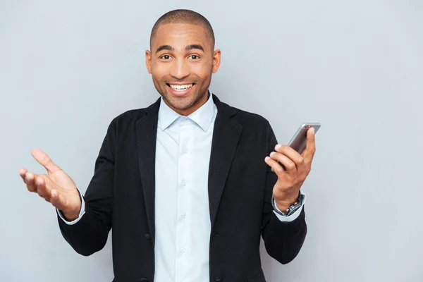 Jeune homme souriant avec téléphone intelligent sur fond gris — Photo