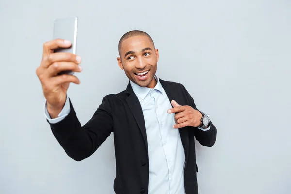 Ung man att göra selfie foto på smartphone över grå bakgrund — Stockfoto