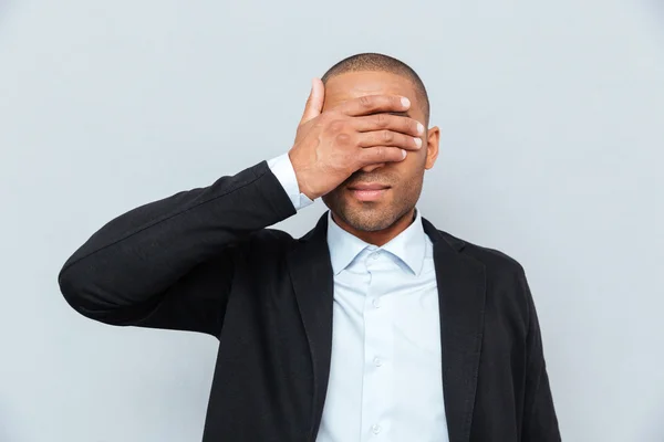 Portrait of a businessman covering eyes isolated on gray background — Stock Photo, Image