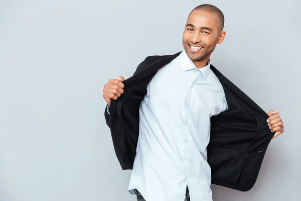 Attraktiver Mann zieht seine Jacke vor grauem Hintergrund aus — Stockfoto