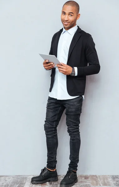 Full length of smiling african american young man using tablet — Stock Photo, Image