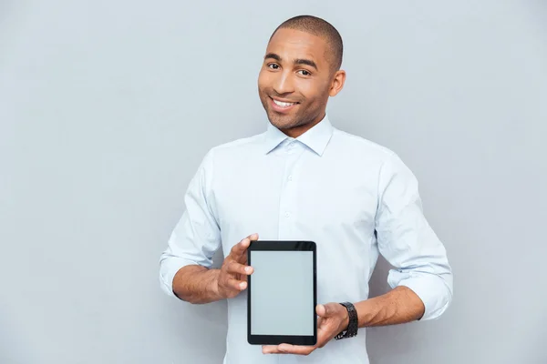 Smiling attractive african american young man holding blank screen tablet — Stock Photo, Image