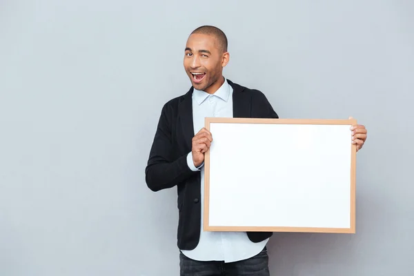 Souriant afro-américain jeune homme clin d'oeil et tenant tableau blanc — Photo