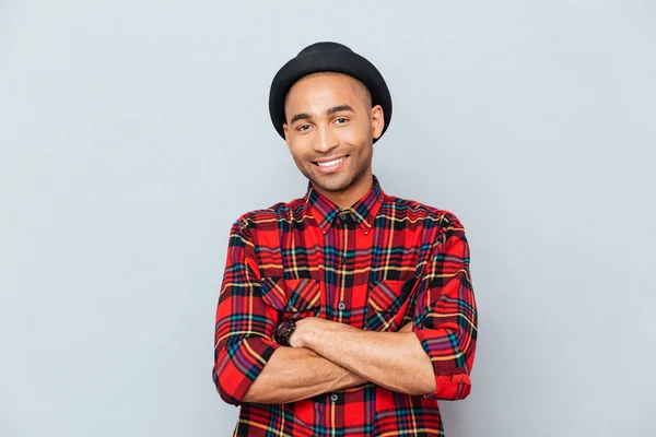 Happy handsome african man in hat standing with arms crossed — Stock Photo, Image