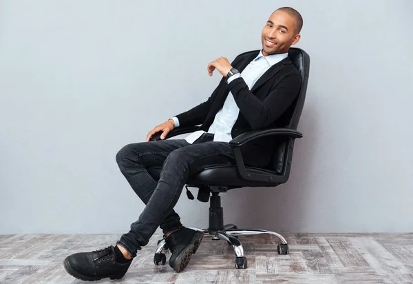 Gelukkig Afro-Amerikaanse jonge man zitten in de stoel van het Bureau van de leer — Stockfoto