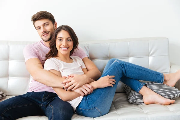 Retrato de una hermosa pareja sonriente sentada en el sofá — Foto de Stock