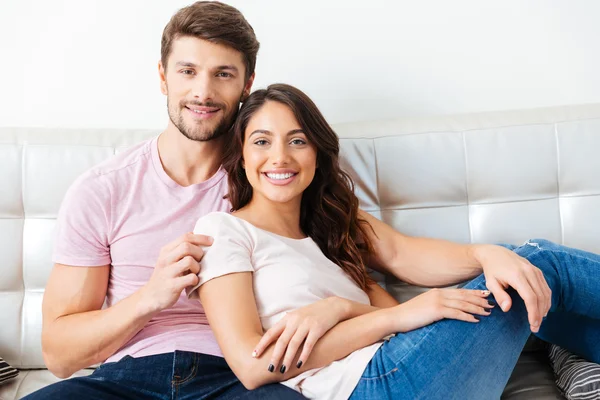 Lächelndes junges Paar auf dem Sofa vor weißem Hintergrund — Stockfoto
