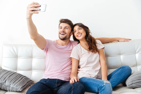 Hermosa pareja joven está haciendo selfie usando un teléfono inteligente — Foto de Stock