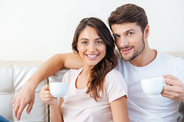 Портрет прекрасной пары на диване, пьющей кофе — стоковое фото