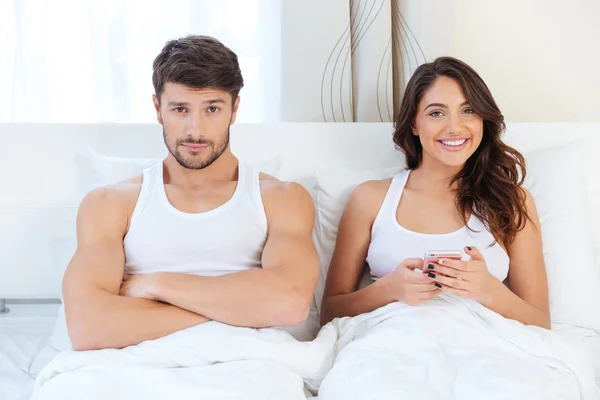 Wütender junger Mann liegt mit einer Frau auf dem Bett — Stockfoto