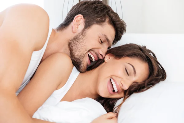 Счастливая пара смеется в постели — стоковое фото