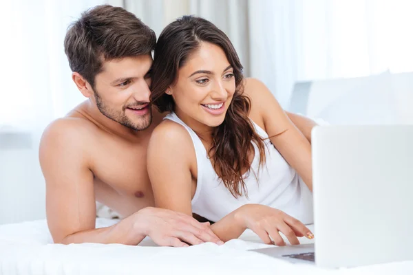 Primer plano retrato de pareja sonriente con portátil en la cama — Foto de Stock