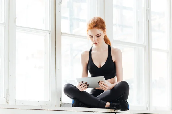 Красивая молодая женщина использует планшетный компьютер после тренировки — стоковое фото