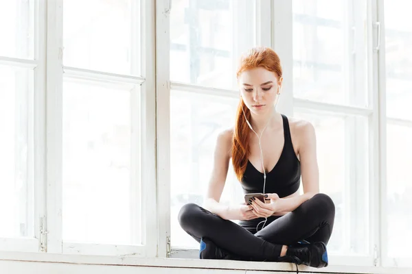 Sportswoman listening to music using smartphone — Stock Photo, Image