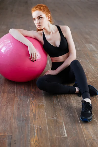 Жінка сидить з м'ячем у спортзалі — стокове фото