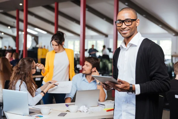 Allegro giovane uomo d'affari africano che utilizza tablet in ufficio — Foto Stock