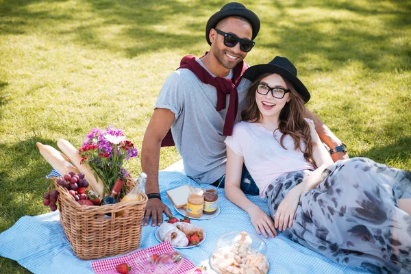 Sonriendo joven pareja teniendo picnic en el césped en el parque — Foto de Stock