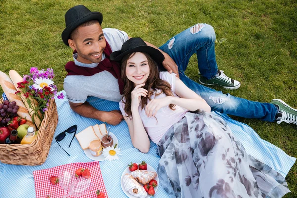 Alegre joven pareja sonriendo y mintiendo teniendo picnic — Foto de Stock