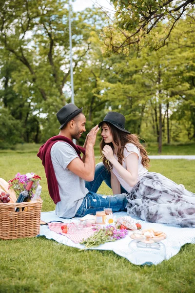 Usmívající se mladý pár s piknik v parku — Stock fotografie