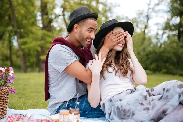 Fröhlicher junger Mann verdeckte Augen seiner Freundin im Park — Stockfoto