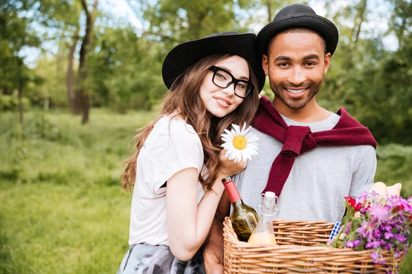 Felice giovane coppia con cesto di bevande, cibo e fiori — Foto Stock