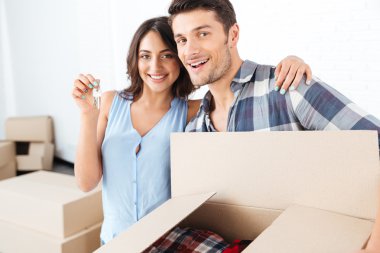 Kameraya bakarak yeni ev sarılma için tuşlarını gösteren çift