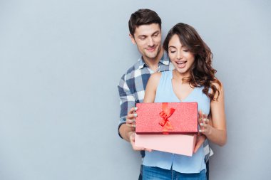Genç kadın hediye sevgilisinden gri arka plan üzerinde alma.