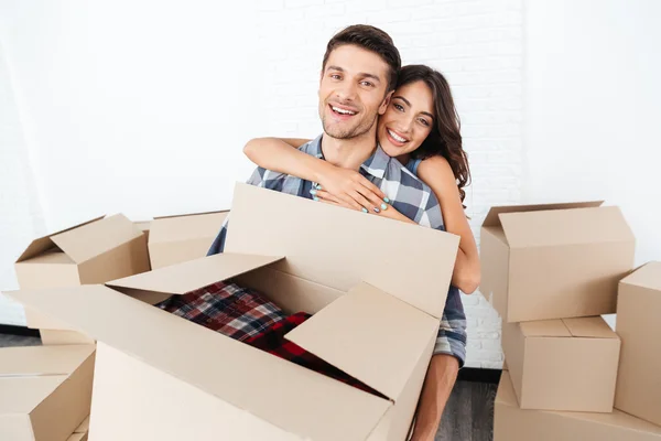 Sonriente pareja joven que lleva cajas de cartón y abrazos —  Fotos de Stock