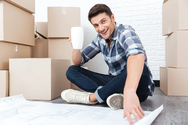 Happy handsome man looking at house construction plan — Stock Photo, Image