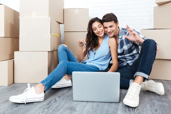 Pareja feliz sentada en el suelo moviéndose en una casa nueva — Foto de Stock