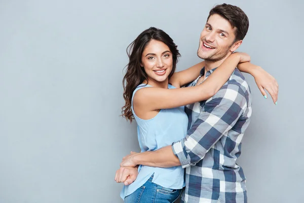 Lässiges junges Paar umarmt sich über grauen Backboden — Stockfoto