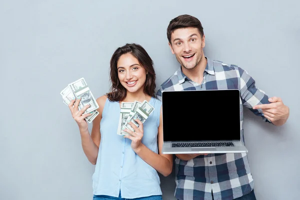 Retrato de feliz pareja joven usando portátil sobre fondo gris — Foto de Stock