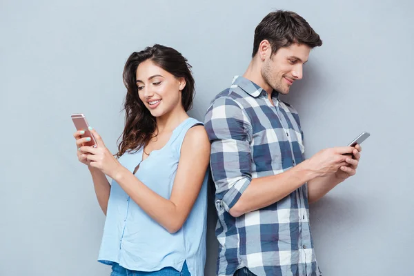 Casal estão olhando para smartphone sobre fundo cinza — Fotografia de Stock