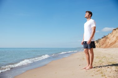 Man standing and relaxing on the beach clipart