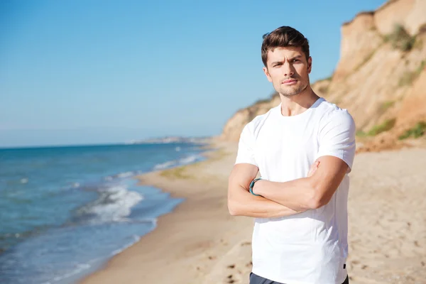 Серьезный молодой человек стоит на пляже — стоковое фото