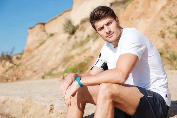 Nadenkend man zittend op het strand — Stockfoto