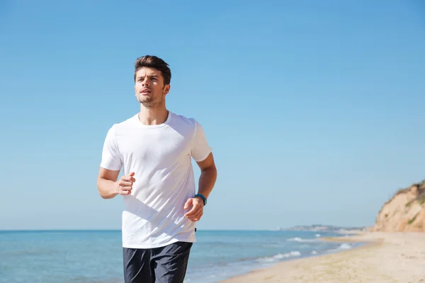 Concentrated young sportsman running on the beach — Stock Photo, Image