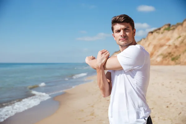 Αυτοπεποίθηση νεαρός αθλητής κάνει ασκήσεις στην παραλία — Φωτογραφία Αρχείου