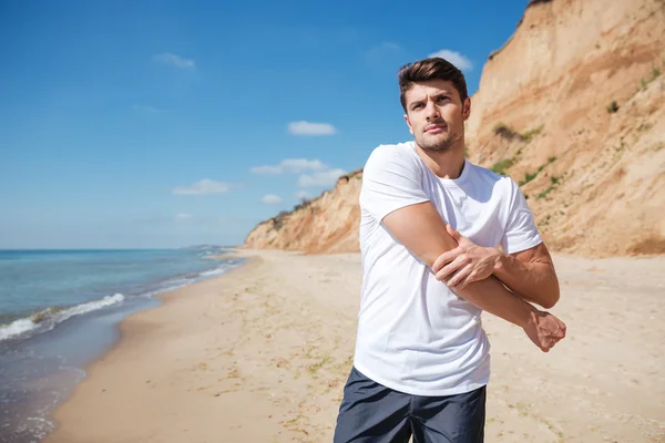 Un jeune homme concentré s'échauffe sur la plage — Photo