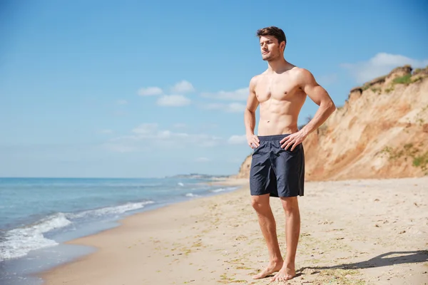 Uvolněné mladý muž, který stojí na pláži — Stock fotografie