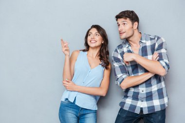 Çift ayakta ve gri arka plan üzerinde bir şeye işaret gülümseyen