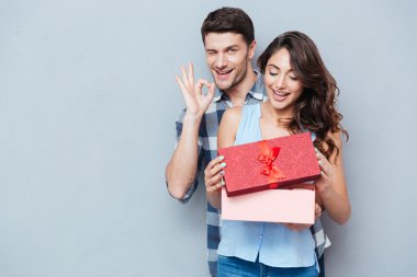 Genç kadın hediye sevgilisinden gri arka plan üzerinde alma.